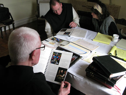 Father Laurence and Dom Richard review comps with Connie in the guesthouse front room